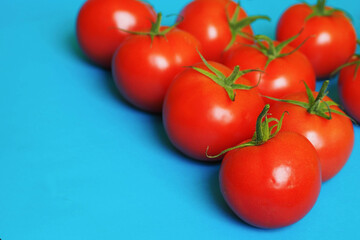 close-up of a lot of ripe round red tomatoes on a blue textural background side view . red raw vegetables