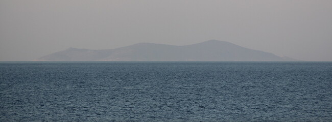 Little island emerging from the calm sea - peaceful shades of blue