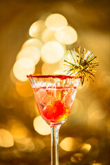 Sherryglas mit Kirsche und goldenem Bokeh im Hintergrund