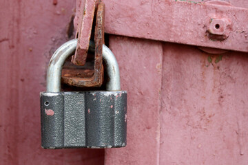 Old padlock on red metal doors with weathered paint. Locked gates, home security concept
