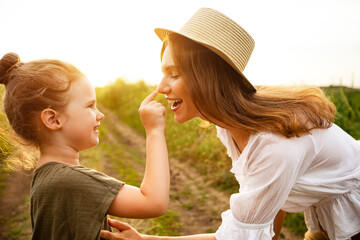 Happy mom and baby playing together in the spring field