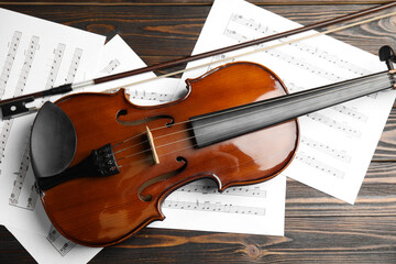 Beautiful violin, bow and note sheets on wooden table, flat lay