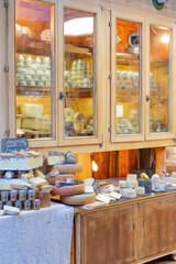 Fototapeta na wymiar Private cheese shop. Many different types of cheese. Outside the wooden Windows, circles, halves, and quarters of cheese are laid out. Healthy delicious food, variety