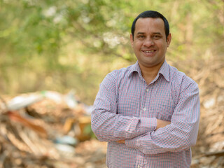 Portrait of happy overweight Indian businessman at the park outdoors