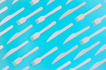 Wooden forks and knives on a turquoise background. Cutlery template. Top view.