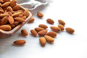 Almonds nuts in wooden bowl on a white wooden table