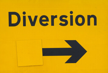 British bright yellow diversion sign with black lettering and an arrow pointing right
