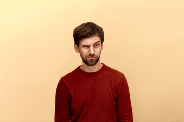 Are you sure. Photo of young man with beard wearing sweater, frowns face, raises eyebrow, looks...