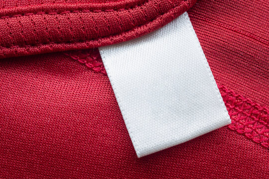 White blank laundry care clothes label on red polyester sport shirt background