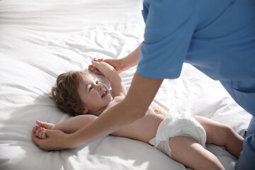 Obraz na płótnie Canvas Orthopedist examining cute little baby on bed