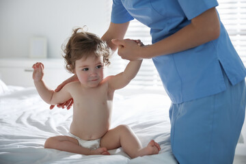 Obraz na płótnie Canvas Orthopedist examining little baby on bed indoors