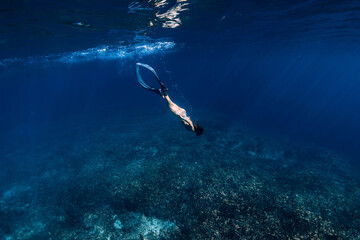 Woman freediver glides underwater in sea. Freediving with fins