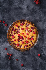 Sweet tasty pie with jellied and fresh raspberry fruits in baking dish, dark stone concrete background, top view