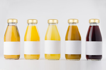 Yellow, orange, red fruit juices large collection in glass bottles with cap, white blank labels in row mock up on white background, template for packaging, advertising, design product, branding.
