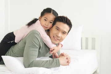 asian family, happy father and daughter embracing lying in bedroom happy activities at home, family concept.