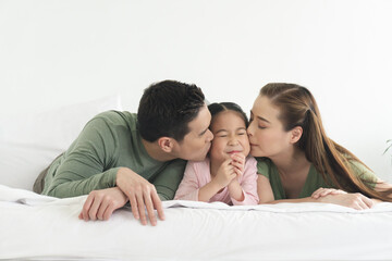 asian family, happy father mather and daughter fragrant cheek lying in bedroom at home.