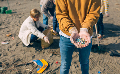 Detail of young man hands showing microplastics on the beach