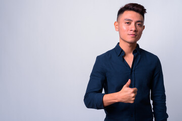 Portrait of young Asian businessman giving thumbs up
