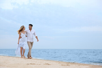 Happy couple having romantic walk on beach. Space for text