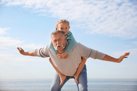 Little Girl Playing With Grandfather On Sea Beach