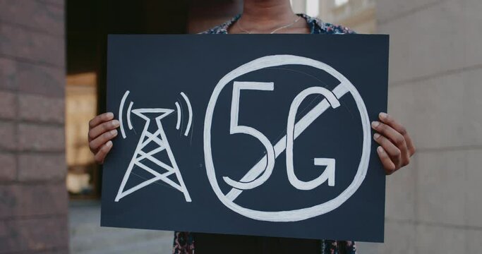 Close up of female hands holding placard with no 5g sign. African american girl doing single protest against new technology and compatible antenna deployment while standing at street