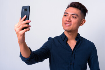 Portrait of happy young Asian businessman taking selfie