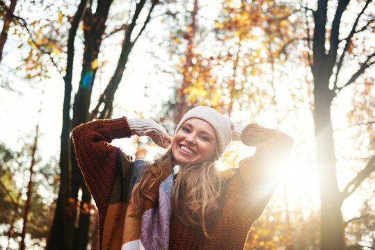 Happy woman in the autumn forest with her hands up