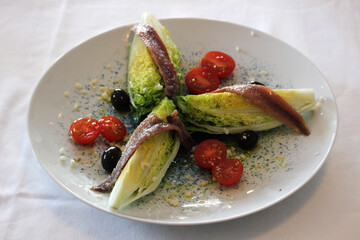 Lettuce hearts with anchovies, olives and cherry tomatoes in salad