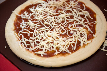 Pizza dough piece with cheese and tomato sauce, close-up.