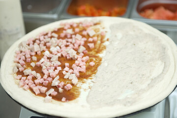 Preparation of pizza dough with pieces of ham on the scales, close-up.