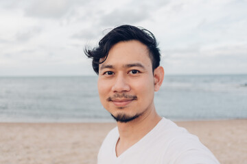 Happy Asian man selfie himself while walking on the beach.