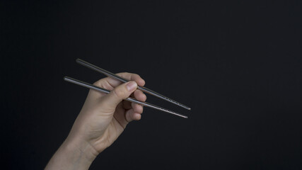 Woman hand holding  metal chopsticks 