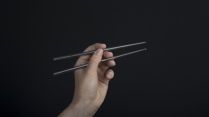 Woman hand holding  metal chopsticks 