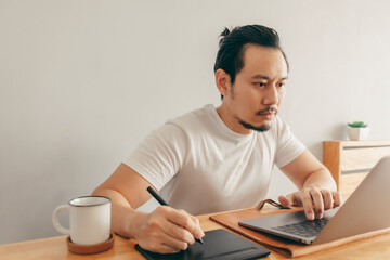Asian man is working with laptop in his apartment bedroom in concept of Work From Home and Work at...