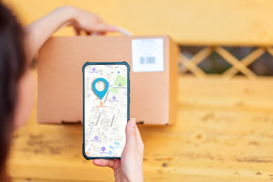 A woman scans the parcel code using her smartphone. Online map on the cellphone. Concept of courier delivery and modern technologies