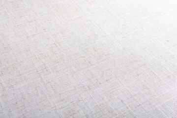 texture of light beige linen fabric at a sharp angle with selective depth of field