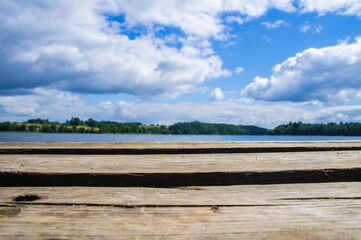 Naklejka na ściany i meble Beautiful wooden pier on the background of a blue forest lake