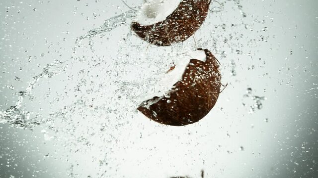 Super slow motion of coconut pieces flying in the air with water splashes. Filmed on high speed cinema camera, 1000 fps.