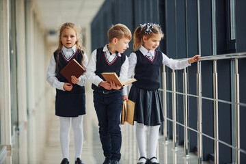 School kids in uniform together with books in corridor. Conception of education