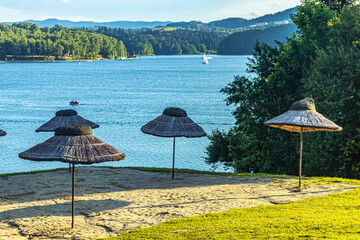 Straw umbrellas on the beach by the lake