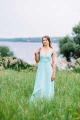 Fototapeta na wymiar Happy girl in a turquoise long dress in a green park