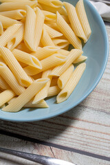 Penne pasta food served on a blue plate on a wooden table close up still