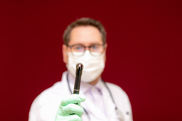 audiologist stethoscope neck wearing glasses latex gloves holds otoscope. Modern medical technology burgundy wall.