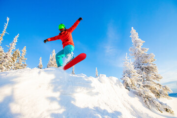 Snowboarder jumps in fresh snow forest. Freeride snowboarding in ski resort