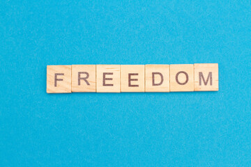 FREEDOM word from wooden blocks on a blue background.