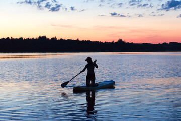 Girl on an inflatable board on the lake at sunset. Sup board.