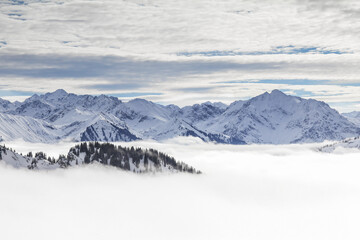 Fototapeta na wymiar Snow covered mountains with inversion valley fog and trees shrouded in mist. Scenic snowy winter landscape in Alps, Allgau, Kleinwalsertal, Bavaria, Germany.