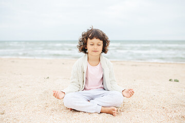 little girl meditating on the beach
