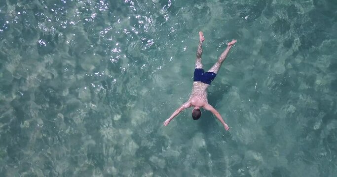 Male body floating in water. Aerial drone shot of drowned guy in the sea. Turquoise clear sea water