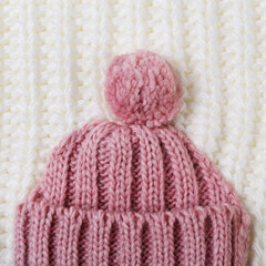 pink knitted hat lies on white knitted fabric, concept